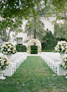 an outdoor ceremony set up with white chairs and flowers