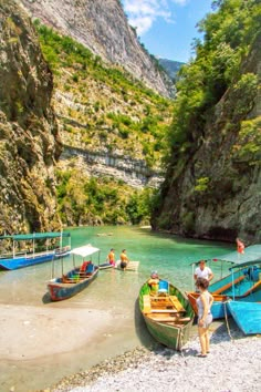 there are many small boats on the water near some cliffs and people in bathing suits