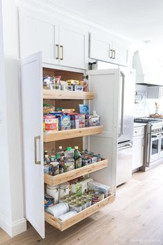 an open pantry door in a kitchen with white cabinets and drawers on the bottom shelf