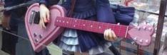 a mannequin holding a pink guitar in front of a store window