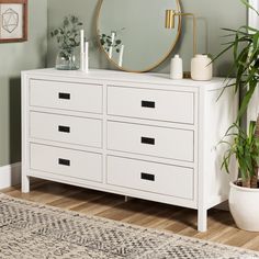 a white dresser with a mirror and plants