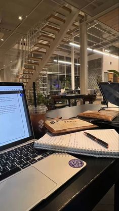 an open laptop computer sitting on top of a wooden desk next to a spiral staircase