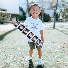 a young boy is holding a skateboard with photos on it and smiling at the camera