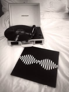 an old record player and vinyl in a suitcase on a bed