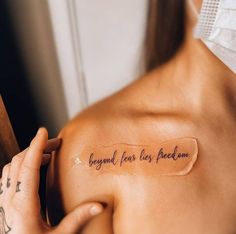 a woman with a tattoo on her shoulder that says, beyond fear lies peace now