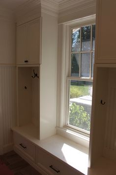 an empty room with white cupboards and drawers in front of a large open window