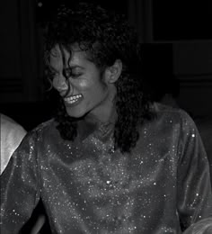 a black and white photo of a woman with long curly hair smiling at the camera