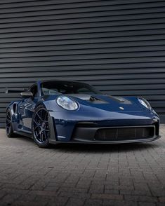 a blue sports car is parked in front of a garage door with its lights on