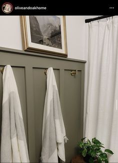 two white towels hanging on the side of a door next to a potted plant