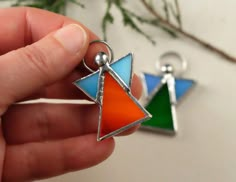 a hand holding two colorful triangle shaped charms