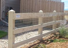 the fence is made of wood and has metal bars on each side, along with gravel