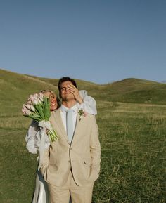 a man and woman are standing in the grass with tulips on their shoulders