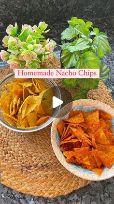 two bowls filled with chips sitting on top of a table next to flowers and plants