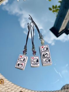 three playing cards hanging from a rope on a blue sky with clouds in the background