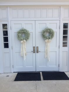 two wreaths on the front doors of a house