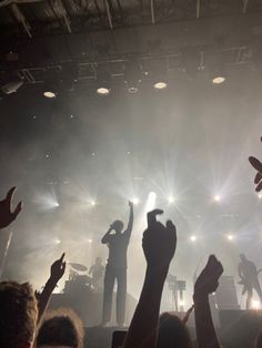 a group of people standing on top of a stage with their hands in the air