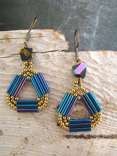 a pair of earrings sitting on top of a piece of wood