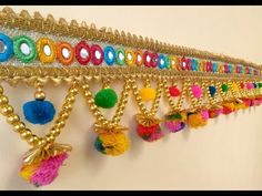 a wall hanging with lots of different colored beads and pom poms on it