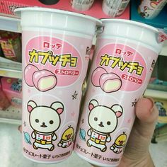 two plastic cups with cartoon characters on them in a store display case, one is pink and the other is white