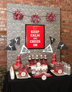 a table topped with lots of red and white items next to a brick wall covered in paper