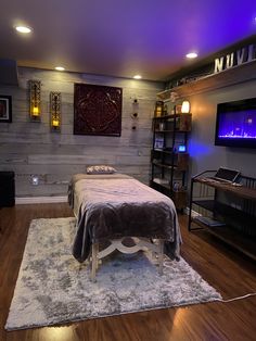 a bed sitting on top of a wooden floor next to a tv mounted above it