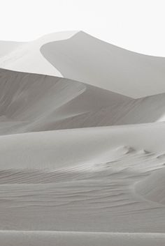 two people are walking through the sand dunes