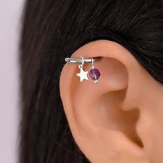 a woman's ear is shown with a star and purple crystal