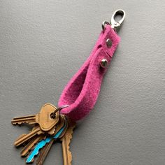 a pink keychain with several keys attached to it and a pair of scissors hanging from the end