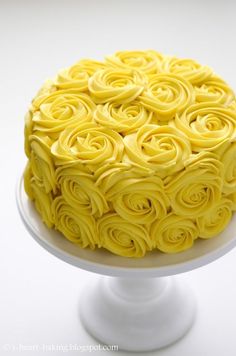 a cake with yellow icing is on a white plate and sits on a pedestal