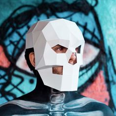 a man wearing a paper mask in front of a graffiti wall