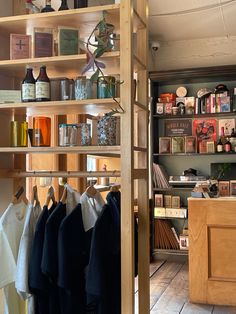 a room with shelves filled with clothes and bottles on top of wooden shelves next to a counter