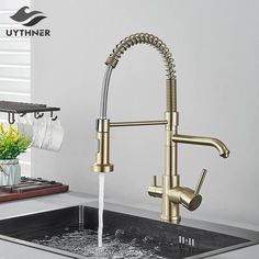 a faucet with water running from it in a kitchen sink next to a potted plant