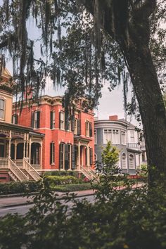 an old red brick house surrounded by trees and bushes with spanish moss hanging from the branches