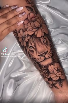 a woman's arm with flowers and a lion tattoo on the left side of her arm