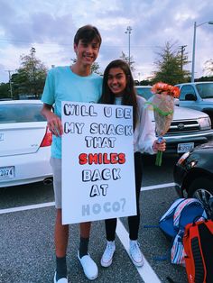 two people standing next to each other holding a sign