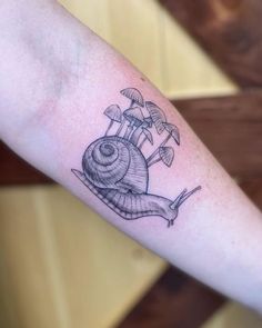 a small snail tattoo on the arm