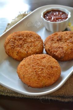 three fried food items on a white plate with dipping sauce in a small bowl next to it