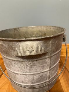 an old metal bucket sitting on top of a wooden table