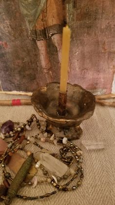 a candle that is sitting on some kind of table with beads and other items around it