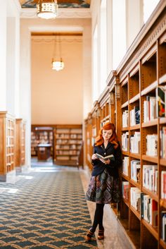 a woman leaning against a book shelf in a library