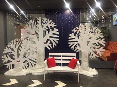 an office lobby decorated with white paper snowflakes and red pillows on the bench