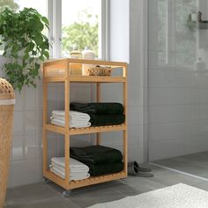 a wooden shelf with towels on it next to a potted plant in a bathroom