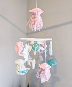 a pink and white baby mobile with sea animals hanging from it's sides in a room