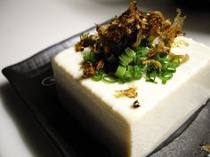 a square piece of cake with green onions and other toppings on top of it