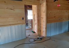 an unfinished room with wood paneling and electrical wires on the floor in front of it