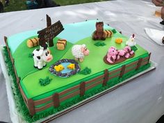 a cake with farm animals on it sitting on top of a white tablecloth covered table