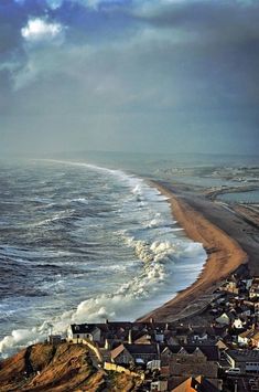 an ocean view from the top of a hill with houses on it and waves coming in