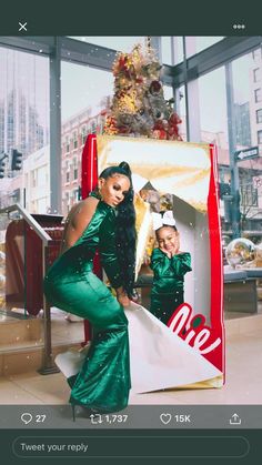 a woman in green dress standing next to a giant coca cola sign with a child on it