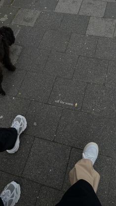 two people standing on the sidewalk with their feet up and one person wearing white sneakers