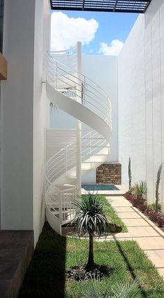 there is a white spiral staircase going up the side of a building with grass in front of it